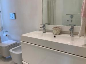a bathroom with a sink and a toilet and a mirror at Rome, Beautiful Apartment in a Vintage Building in Lido di Ostia