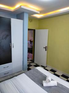 um quarto com uma cama, uma televisão e um piso de xadrez em Greenstar Homes em Kisii
