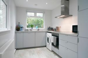eine weiße Küche mit Waschmaschine und Trockner in der Unterkunft Close to City Centre Stylish and Cosy Home in Belfast