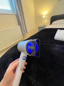 a person holding a blow dryer in front of a bed at Cosy two bedrooms flat suitable for a short trip in Portsmouth