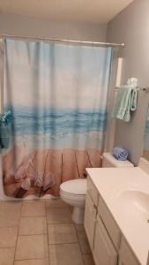 a bathroom with a toilet and a shower curtain at Scenic Views, Hot Tub, Balcony, And Beach Time! in Pensacola