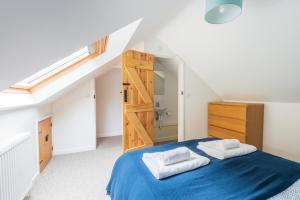 a bedroom with a blue bed with two towels on it at Riverside Bothy In Heart of Scenic Harbour Village in Solva