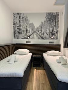 2 camas en una habitación con una foto en la pared en Hotel Titus City Centre en Ámsterdam