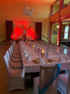 a long dining room with white tables and chairs at Mansfelder Hof in Lutherstadt Eisleben