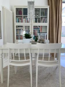 a white dining room table and two white chairs at Rome, Beautiful Apartment in a Vintage Building in Lido di Ostia