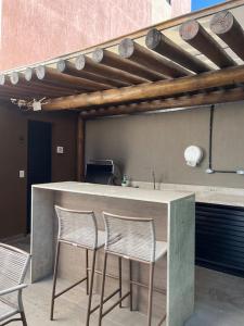 a kitchen with three chairs and a counter with a sink at Flat 207 Villa del Porto in Porto De Galinhas +26 photos