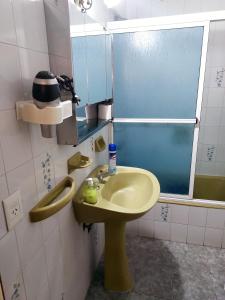 Un baño con un lavabo amarillo y un espejo. en Manilo House, en Mar del Plata