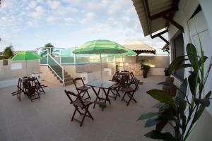 eine Terrasse mit Tischen, Stühlen und einem Sonnenschirm in der Unterkunft Araras Praia Hotel in Aracaju