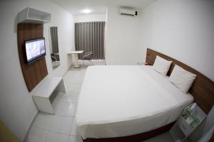 une chambre d'hôtel avec un lit et une télévision dans l'établissement Araras Praia Hotel, à Aracaju