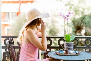 a young girl in a hat sitting at a table at King Othon Boutique Hotel in Nafplio