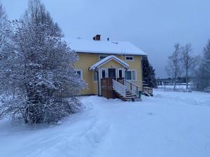 uma casa com neve no chão em frente dela em Apartment MUMMOLA em Rovaniemi