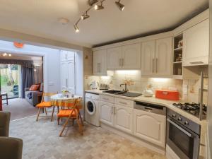 a kitchen with white cabinets and a table and a dining room at Lavender Cottage in Hailsham