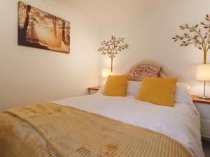 a bedroom with a bed with yellow pillows at Lavender Cottage in Hailsham