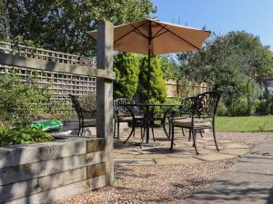a table and chairs with an umbrella in a garden at Lavender Cottage in Hailsham
