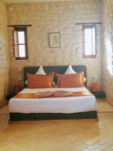 ein großes Bett in einem Schlafzimmer mit zwei Fenstern in der Unterkunft Riad Mamy Wababi in Essaouira