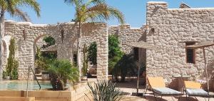 ein Steingebäude mit Stühlen und einem Pool in der Unterkunft Riad Mamy Wababi in Essaouira