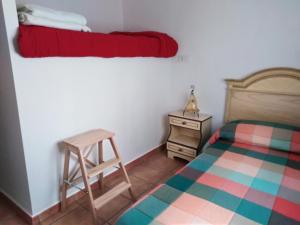 1 dormitorio con cama, escalera y taburete en Casas del Madroño en Cazalla de la Sierra