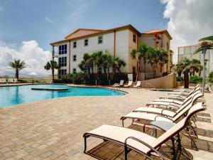 Una fila de sillas junto a una piscina. en Beach Club #206A, en Pensacola Beach