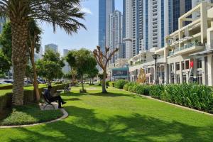a person sitting on a bench in a park with palm trees at Manzil - 1BR in The Bay with Canal View nr Dubai Mall in Dubai
