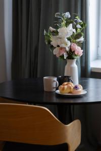 einen Tisch mit einer Vase Blumen und einem Teller Donuts in der Unterkunft Comfortable and Modern Orange Studio in Warsaw by Renters in Warschau