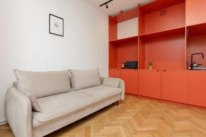 a living room with a couch and orange cabinets at Comfortable and Modern Orange Studio in Warsaw by Renters in Warsaw