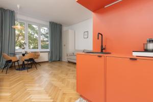 eine orangefarbene Küche und ein Esszimmer mit einem Tisch in der Unterkunft Comfortable and Modern Orange Studio in Warsaw by Renters in Warschau