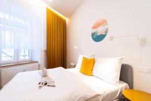 a bedroom with a bed with white sheets and yellow pillows at Cosy Apartment Koliste 25 in Brno