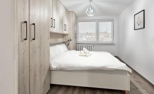 Un dormitorio blanco con una gran cama blanca y una ventana en Winogrady Loft Apartment, en Poznan