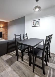 a dining room with a black table and chairs at Winogrady Loft Apartment in Poznań