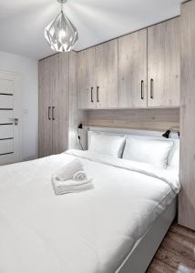 a bedroom with a large white bed with wooden cabinets at Winogrady Loft Apartment in Poznań