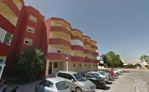 a parking lot with cars parked in front of a building at Espanatour MENORCA in Dehesa de Campoamor