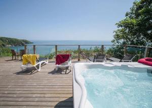 a deck with a swimming pool and chairs and the ocean at Leonards Cove in Stoke Fleming