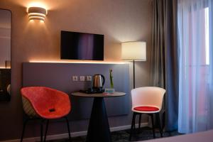 ピテシュティにあるibis Styles Pitesti Argesの椅子2脚、テーブル、テレビが備わる客室です。