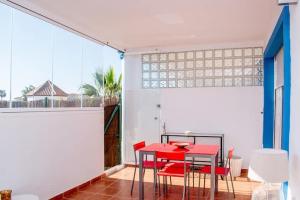 une salle à manger avec une table rouge et des chaises rouges dans l'établissement Apartamento en planta baja, à Estepona