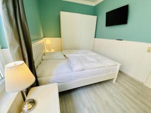 ein kleines Schlafzimmer mit einem weißen Bett und einem TV in der Unterkunft Berringer, Krabbe, direkt an der Promenade in Warnemünde