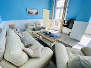 ein Wohnzimmer mit einem weißen Sofa und einem Tisch in der Unterkunft Berringer, Krabbe, direkt an der Promenade in Warnemünde