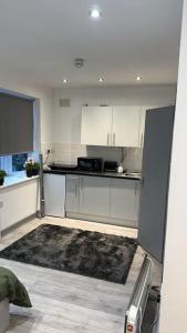 eine Küche mit weißen Schränken und einem Teppich in der Unterkunft Modern studio flat in Romford in Havering atte Bower