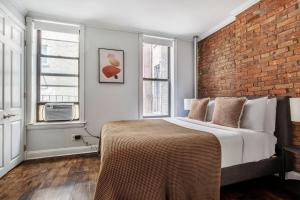 - une chambre avec un lit et un mur en briques dans l'établissement West Village 2br w wd nr shopping NYC-1274, à New York