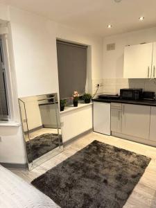 a kitchen with white cabinets and a black rug at Modern studio flat in Romford in Havering atte Bower