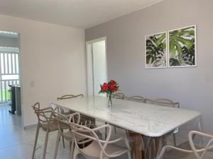 a dining room table with chairs and a vase with flowers at Apartamento 1 quadra do mar in Pontal do Paraná