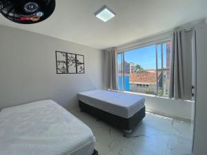 a bedroom with two beds and a large window at Apartamento 1 quadra do mar in Pontal do Paraná