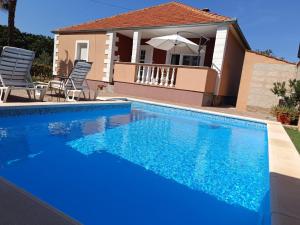 einen Pool mit blauem Wasser vor einem Haus in der Unterkunft Holiday Home Merie with pool in Benkovac