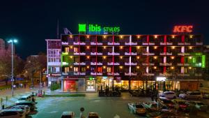 a building with a lot of cars parked in a parking lot at ibis Styles Pitesti Arges in Piteşti