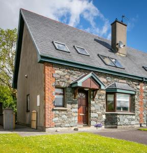 uma casa de pedra com uma porta vermelha e janelas em Delightful cottage just steps from Kenmare town em Kenmare