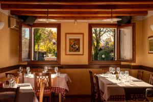 a dining room with tables and chairs and two windows at Locanda al Convento in Favaro Veneto