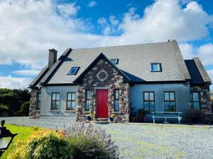 a house with a red door and a bench at Stone fronted detached cottage just over 2 miles from Mulranny village in Mulranny