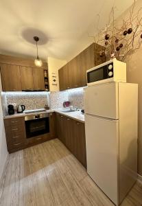 uma cozinha com um frigorífico branco e um micro-ondas em Petkovi Аpartments, Borovets Gardens - One-bedroom and Two-bedroom apartments em Borovets