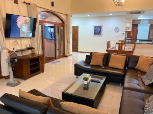 a living room with a couch and a tv at Pattaya Beach Pool Villa At Pattaya in Pattaya South