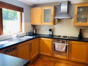 a kitchen with wooden cabinets and a sink and a stove at 3 bedroomed home just 15 mins walk from Kenmare town in Kenmare