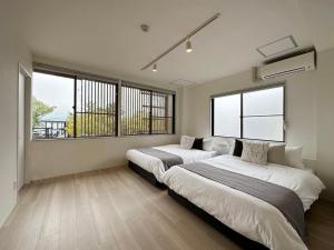 two beds in a room with two windows at bHOTEL Kaniwasou 201 2BR Apt, Near Itsukushima Shrine, For 12 Ppl in Hatsukaichi